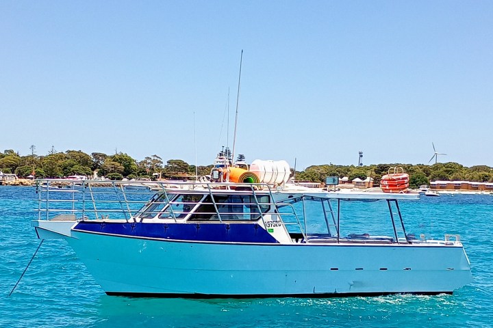 a blue and white boat sitting next to a body of water
