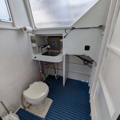 Small boat bathroom with toilet, sink, and patterned floor.