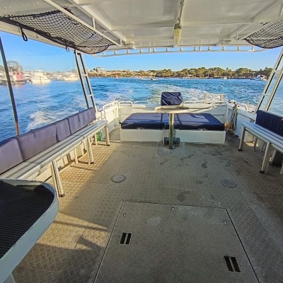 Open boat interior with benches and table, surrounded by water and shoreline in the background.
